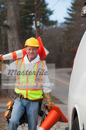 Communications worker moving traffic cones around his truck