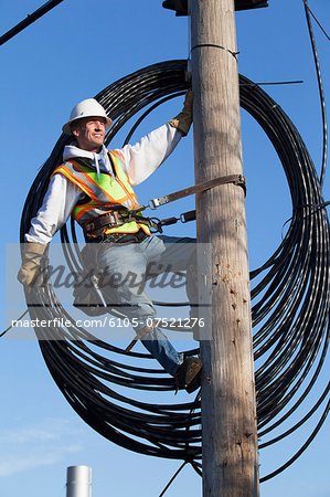 Cable lineman preparing to install new cable from power pole