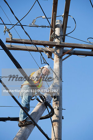 Cable lineman installing new suspension wire from power pole brace