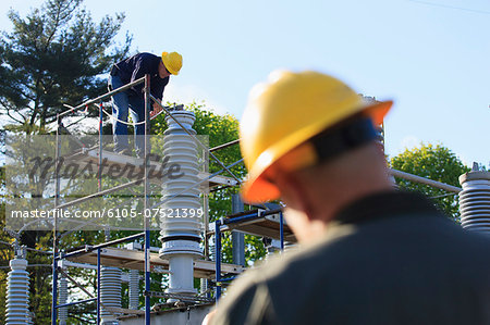 Power engineer performing maintenance on fluid filled high voltage insulator, Braintree, Massachusetts, USA