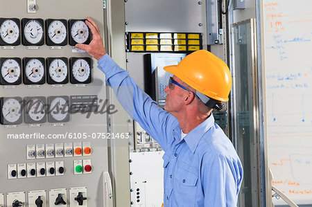 Electrical engineer inspecting power plant controls in central operations room of power plant