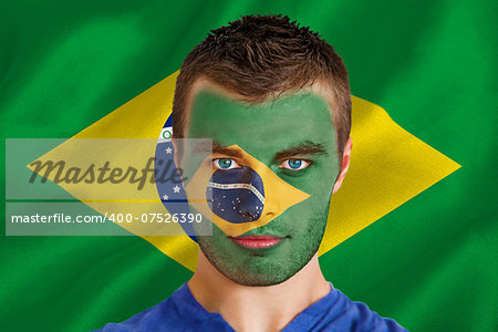 Composite image of serious young brasil fan with facepaint against digitally generated brazilian national flag