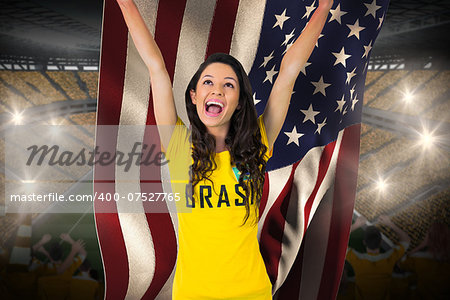 Excited football fan in brasil tshirt holding usa flag against vast football stadium with fans in yellow