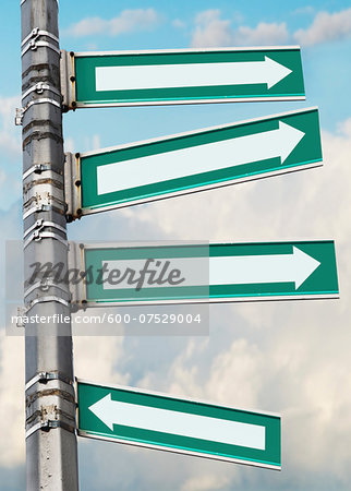 Arrow signs on a pole, showing different directions against sky