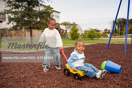 Boy Pulling Younger Brother in Wagon at Playground, Maryland, USA