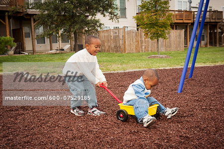 Boy Pulling Brother in Wagon at Playground, Maryland, USA