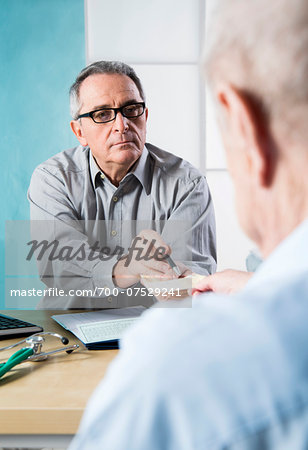 Senior, male doctor conferring with male patient in office, Germany