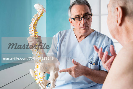 Senior, male doctor discussin spinal cord with senior, male patient, in office, Germany