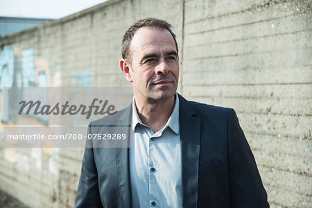 Portrait of businessman standing next to stone wall outdoors, Germany