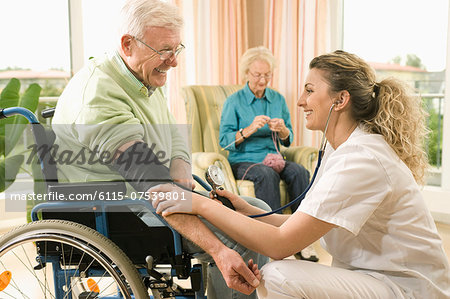 Nurse checks senior man's blood pressure in nursing home, Bavaria, Germany