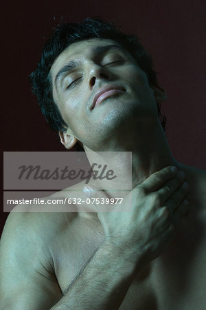 Barechested man with hand on throat, eyes closed