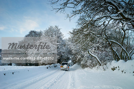 Four wheel drive vehicle in snow-covered lane in Swinbrook, The Cotswolds, UK