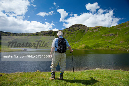Tourist on nature trail in lakeland countryside at Easedale Tarn lake in the Lake District National Park, Cumbria, UK Tourist on nature trail in lakeland countryside at Easedale Tarn lake in the Lake District National Park, Cumbria, UK