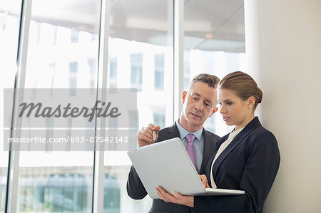 Business colleagues using laptop in office