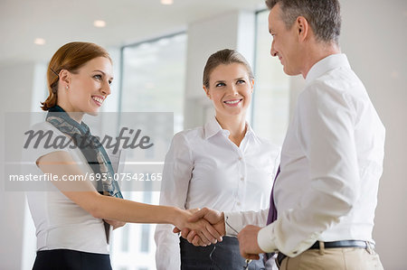 Happy business partners shaking hands in office