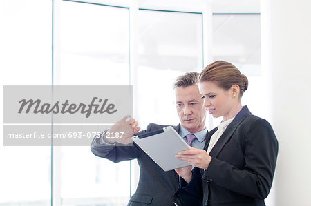 Businessman using tablet PC with female colleague in office Businessman using tablet PC with female colleague in office