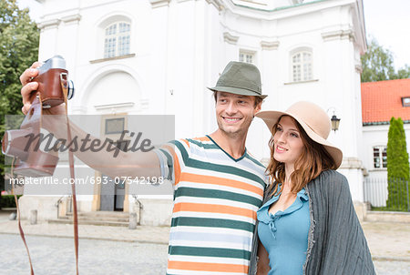 Tourist couple taking self portrait outside St. Casimir Church, Warsaw, Poland