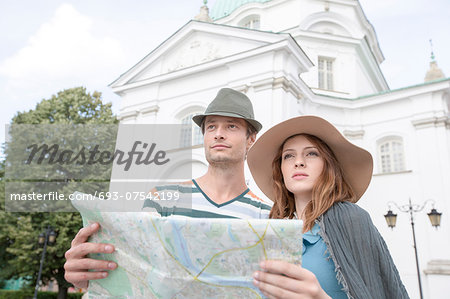 Tourist couple holding map outside St. Casimir Church, Warsaw, Poland