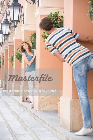 Tourist couple playing hide-and-seek amongst columns