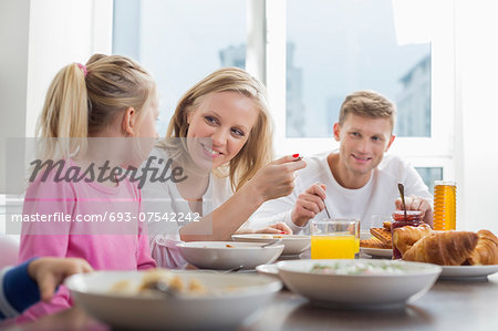 Happy family with children having breakfast at table