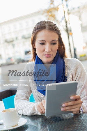 Beautiful woman using tablet PC at sidewalk cafe