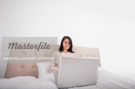 Young woman using laptop on bed