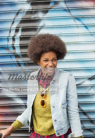 Woman laughing in front of graffiti wall