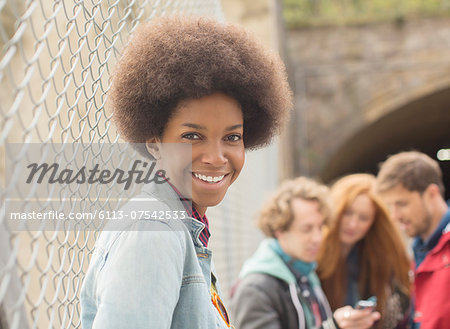 Woman smiling by chain link fence with friends in background