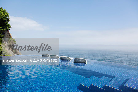 Lounge chairs in infinity pool overlooking ocean