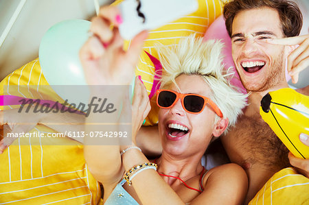 Couple taking self-portraits in bed at party