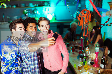 Men taking self-portraits with camera phone at party