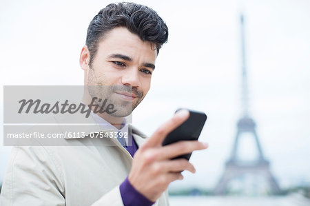 Businessman using cell phone by Eiffel Tower, Paris, France