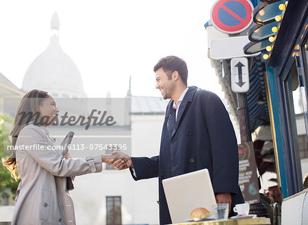 Business people shaking hands on city street