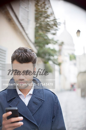 Businessman using cell phone on city street