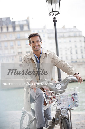 Businessman on bicycle along Seine River, Paris, France