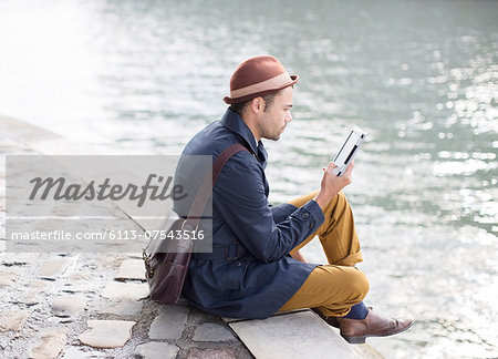 Man using digital tablet along river