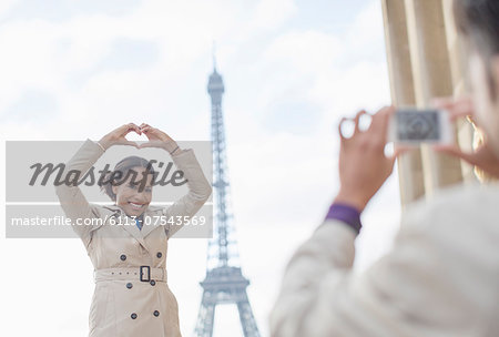 Man photographing girlfriend in front of Eiffel Tower, Paris, France