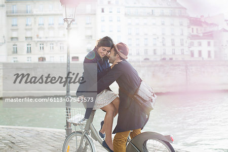 Couple hugging on bicycle along Seine River, Paris, France