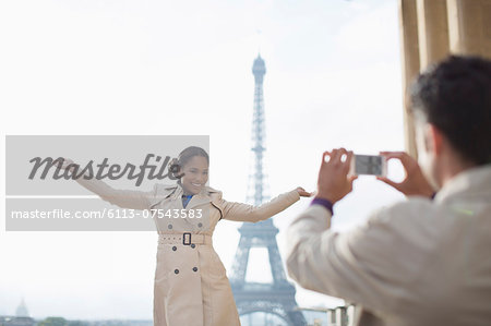 Man photographing girlfriend in front of the Eiffel Tower, Paris, France