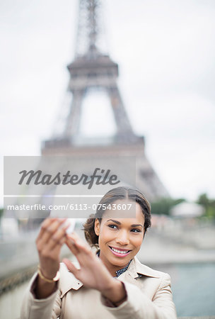 Woman taking self-portrait in front of Eiffel Tower, Paris, France