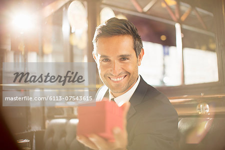 Well-dressed man holding jewelry box in restaurant