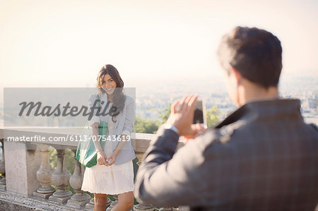 Man photographing girlfriend with Paris in background