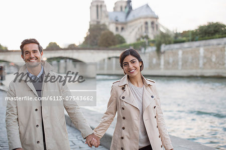 Couple holding hands along Seine River near Notre Dame Cathedral, Paris, France