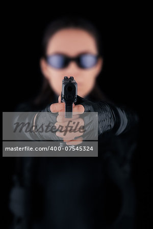 Woman in a black leather suit pointing a gun at the camera