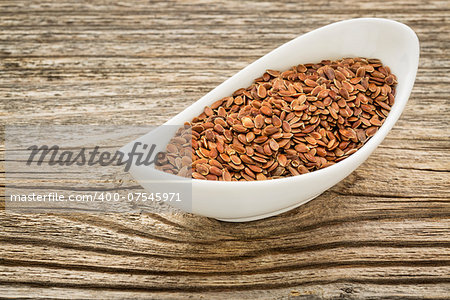 brown flax seeds in a small ceramic bowl against grained wood