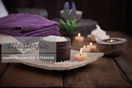 Spa and wellness setting with natural bath salt, candles, towels and flower. Wooden dayspa nature set