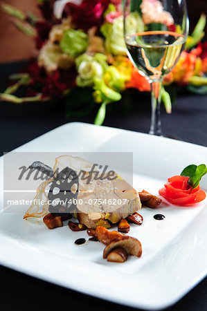 Juicy goose liver on a plate and glass of white wine