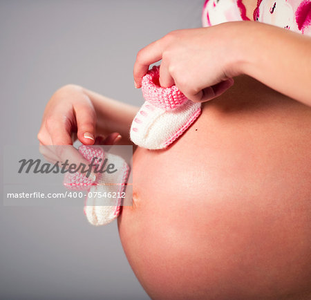 Pregnant woman holding a pair of pink baby booties
