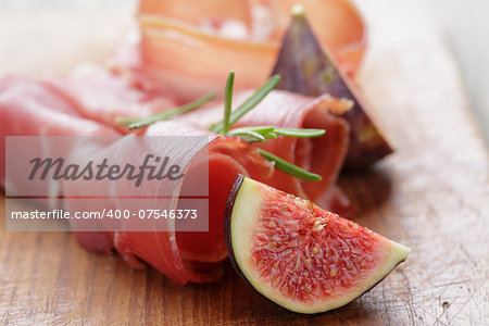 dried jamon slices with figs on wood table, spanish traditional food