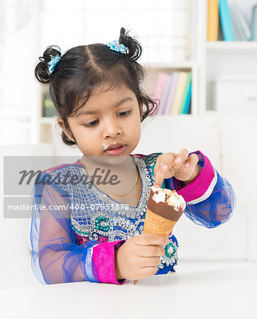 Eating ice cream. Indian Asian girl enjoying an ice cream at home.